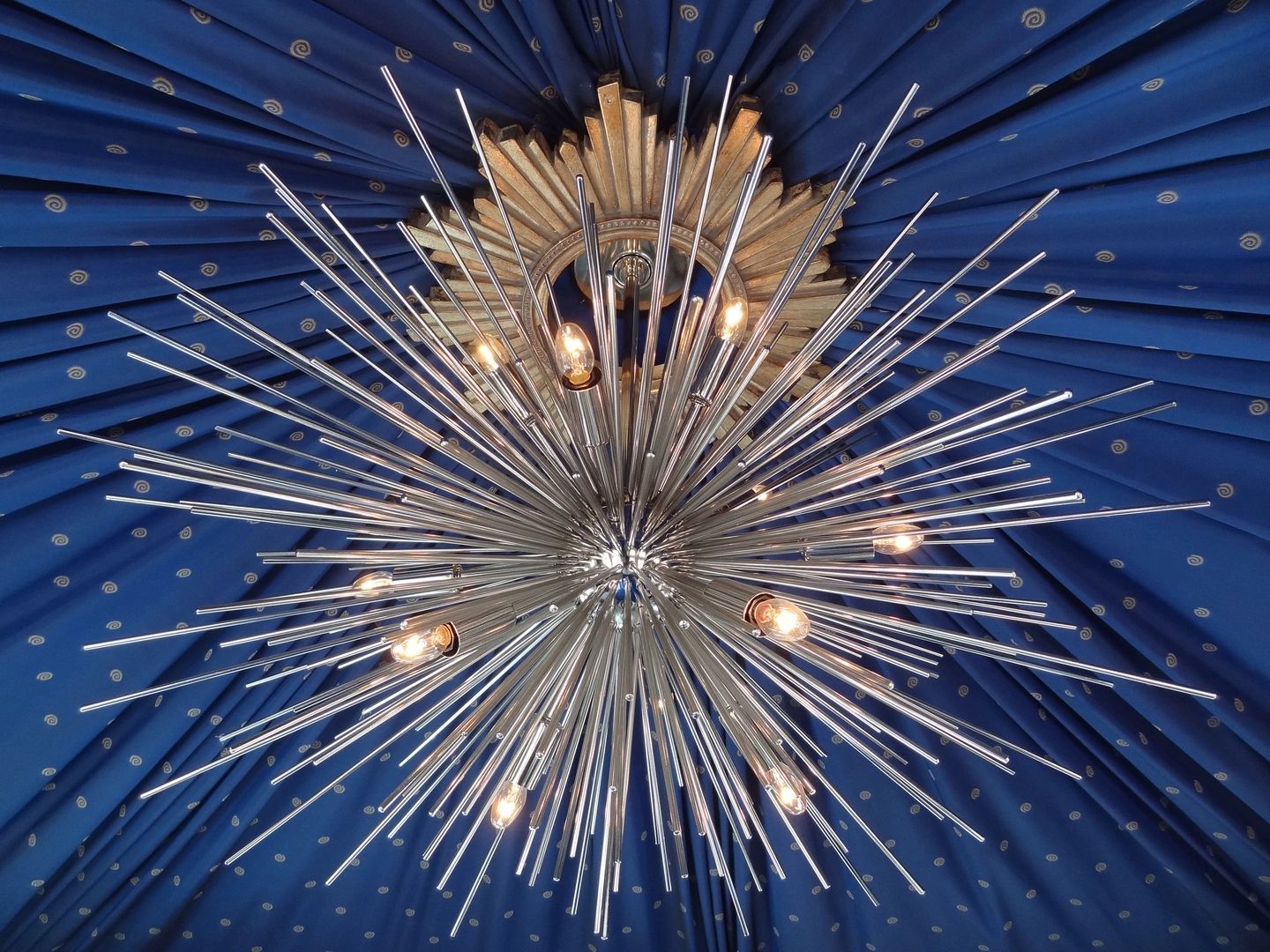 Ornate starburst chandelier against a deep blue ceiling